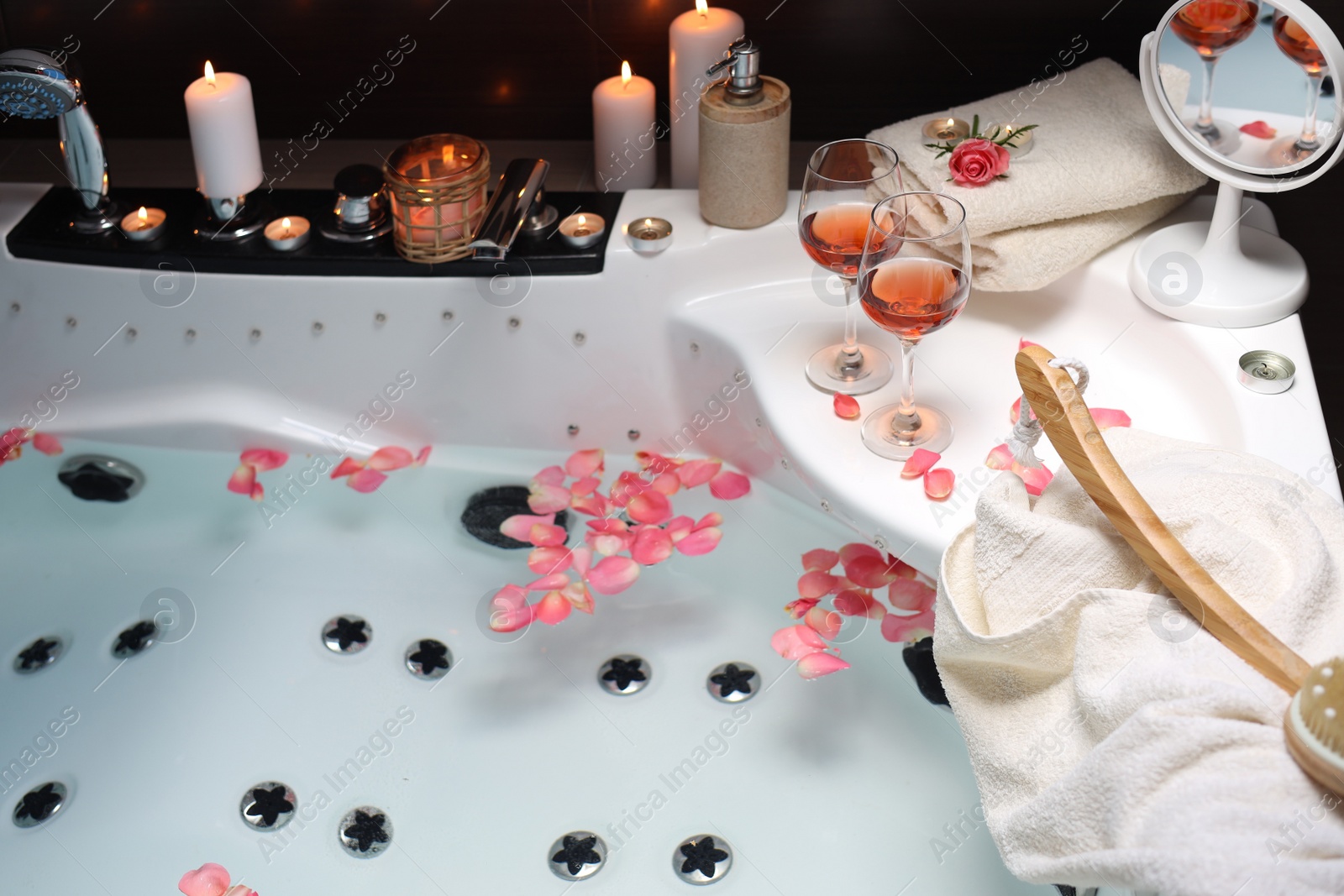 Photo of Bathtub with glasses of wine and candles indoors. Romantic atmosphere