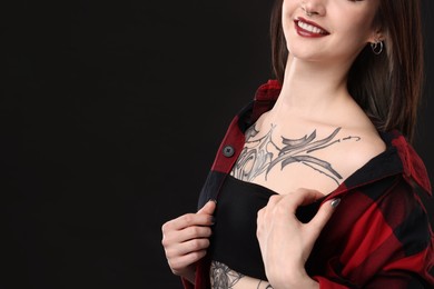 Smiling woman with cool tattoos on black background, closeup. Space for text