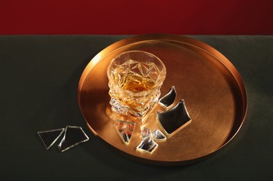 Glass of alcohol drink and shards of broken mirror on soft surface, above view