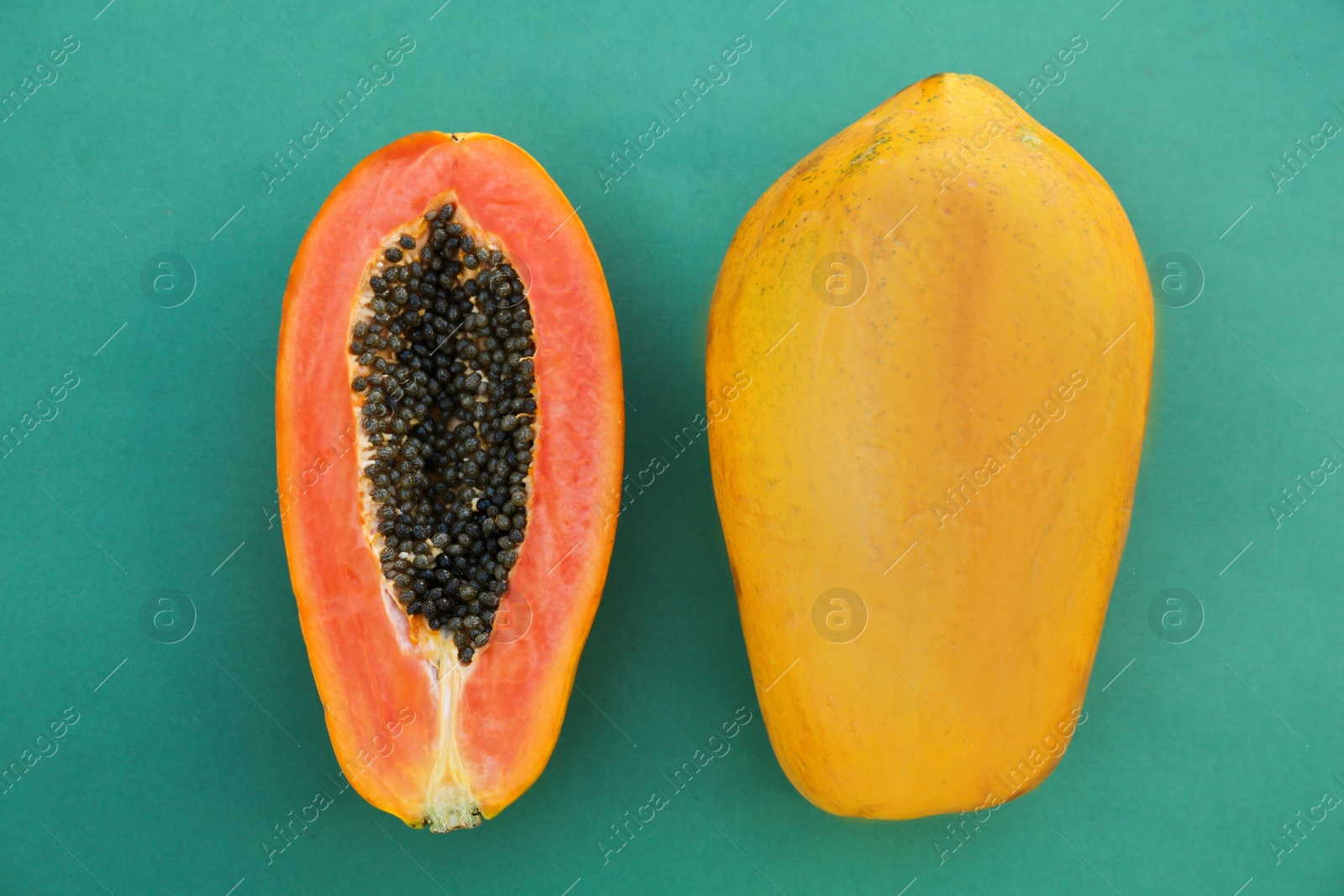 Photo of Fresh ripe cut and whole papaya fruits on light blue background, flat lay