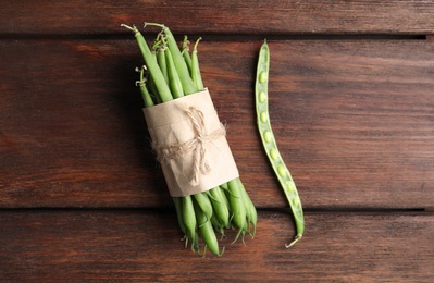 Photo of Fresh green beans on wooden table, flat lay