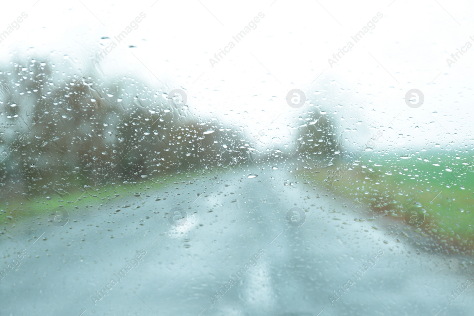 Photo of Blurred view of suburban road through wet car window. Rainy weather
