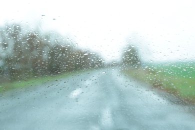 Blurred view of suburban road through wet car window. Rainy weather