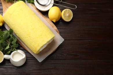 Photo of Delicious cake roll, lemons, mint and powdered sugar on wooden table, flat lay. Space for text