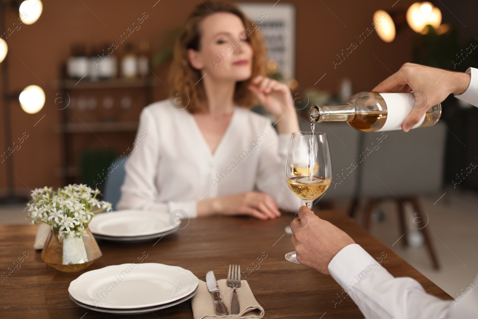 Photo of Waiter pouring wine into glass for client at restaurant