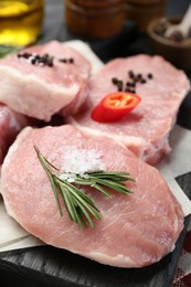 Photo of Pieces of raw pork meat with chili pepper and spices on board, closeup