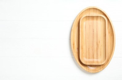 Photo of Empty clean wooden dishware on white table, top view. Space for text