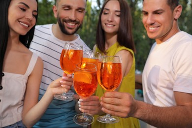 Photo of Friends clinking glasses of Aperol spritz cocktails outdoors