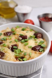 Photo of Tasty sausage casserole with green onion in baking dish on white table, closeup