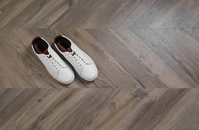 Photo of Pair of stylish sports shoes on wooden floor, top view. Space for text