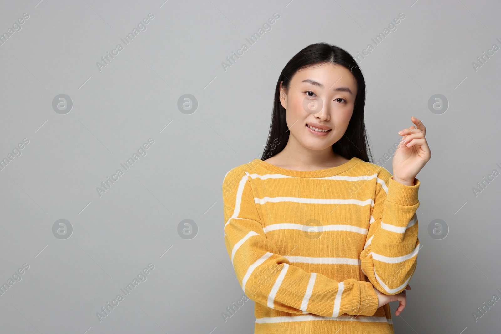 Photo of Portrait of smiling woman on grey background. Space for text