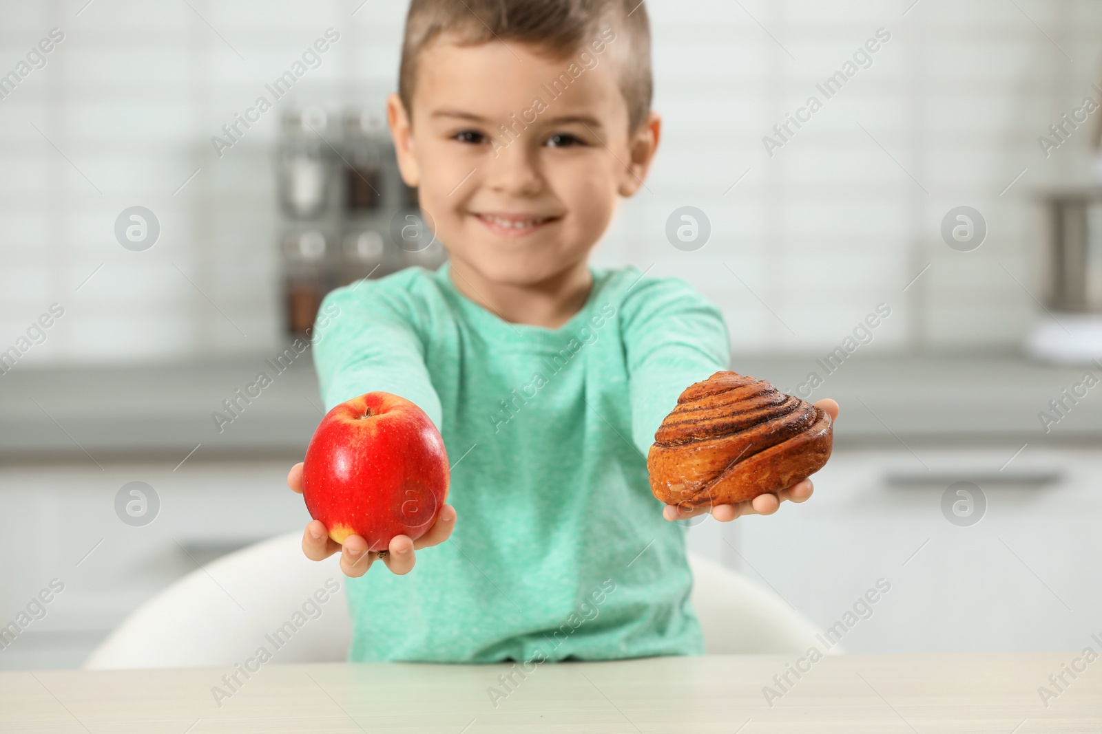 Photo of Little boy with pastry and apple at home. Diabetes diet