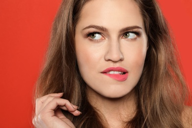 Young woman wearing beautiful lipstick on color background