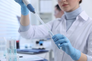 Photo of Scientist dripping sample into test tube in laboratory, closeup