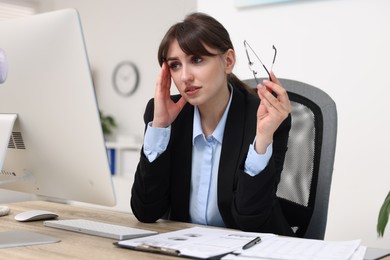 Overwhelmed woman with glasses at table in office