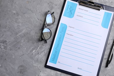 Photo of Medical prescription form with empty fields, glasses and pen on grey textured table, flat lay. Space for text