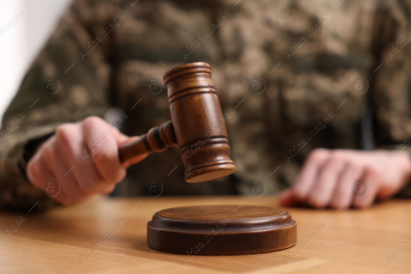 Photo of Law concept. Man in military uniform with gavel at wooden table, closeup