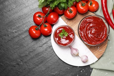 Photo of Organic ketchup in bowls and ingredients on black table, flat lay with space for text. Tomato sauce