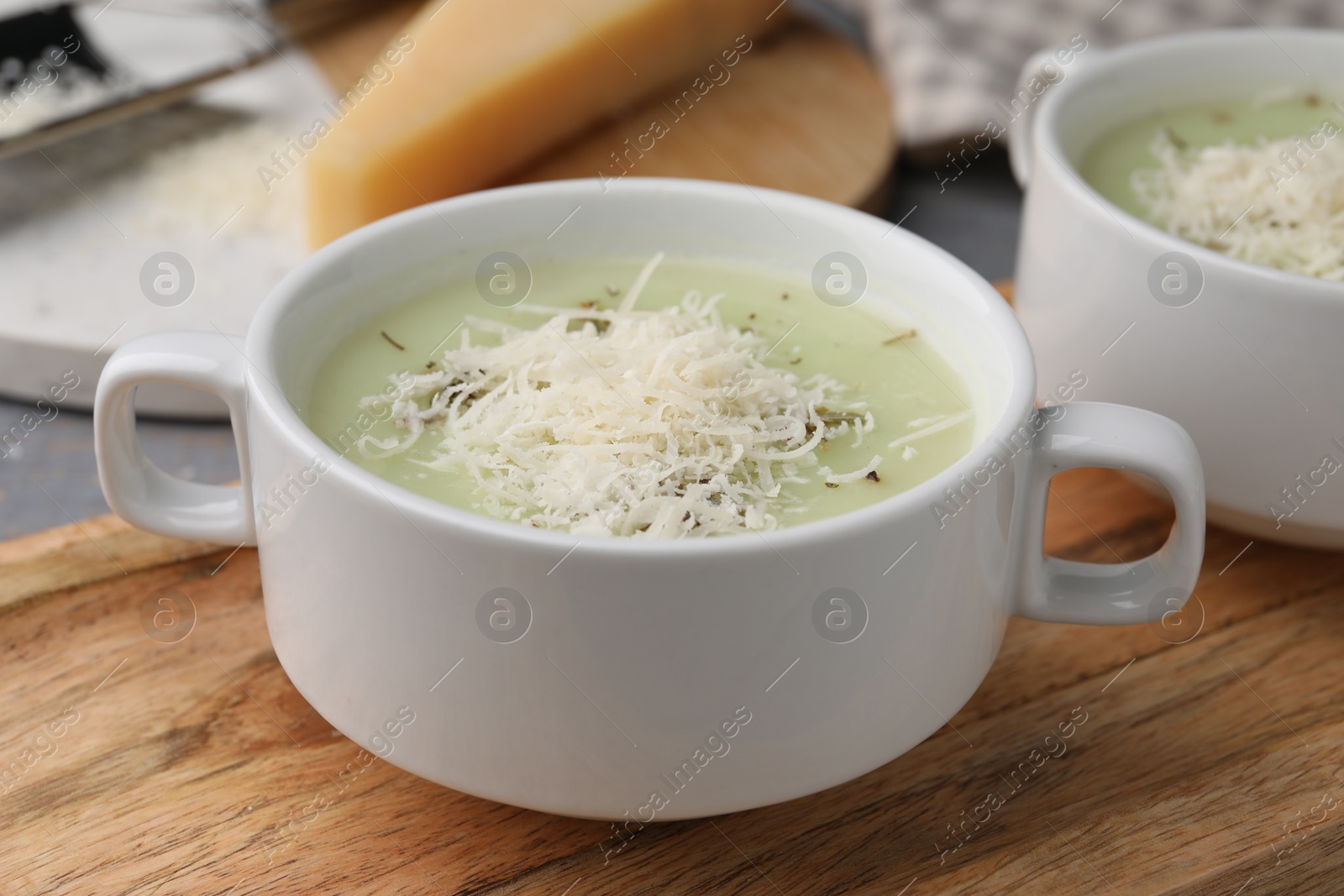 Photo of Delicious cream soup with parmesan cheese in bowls on table, closeup