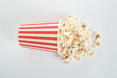 Photo of Overturned paper cup with delicious popcorn isolated on white