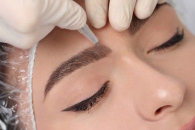 Photo of Young woman during procedure of permanent eyebrow makeup, closeup
