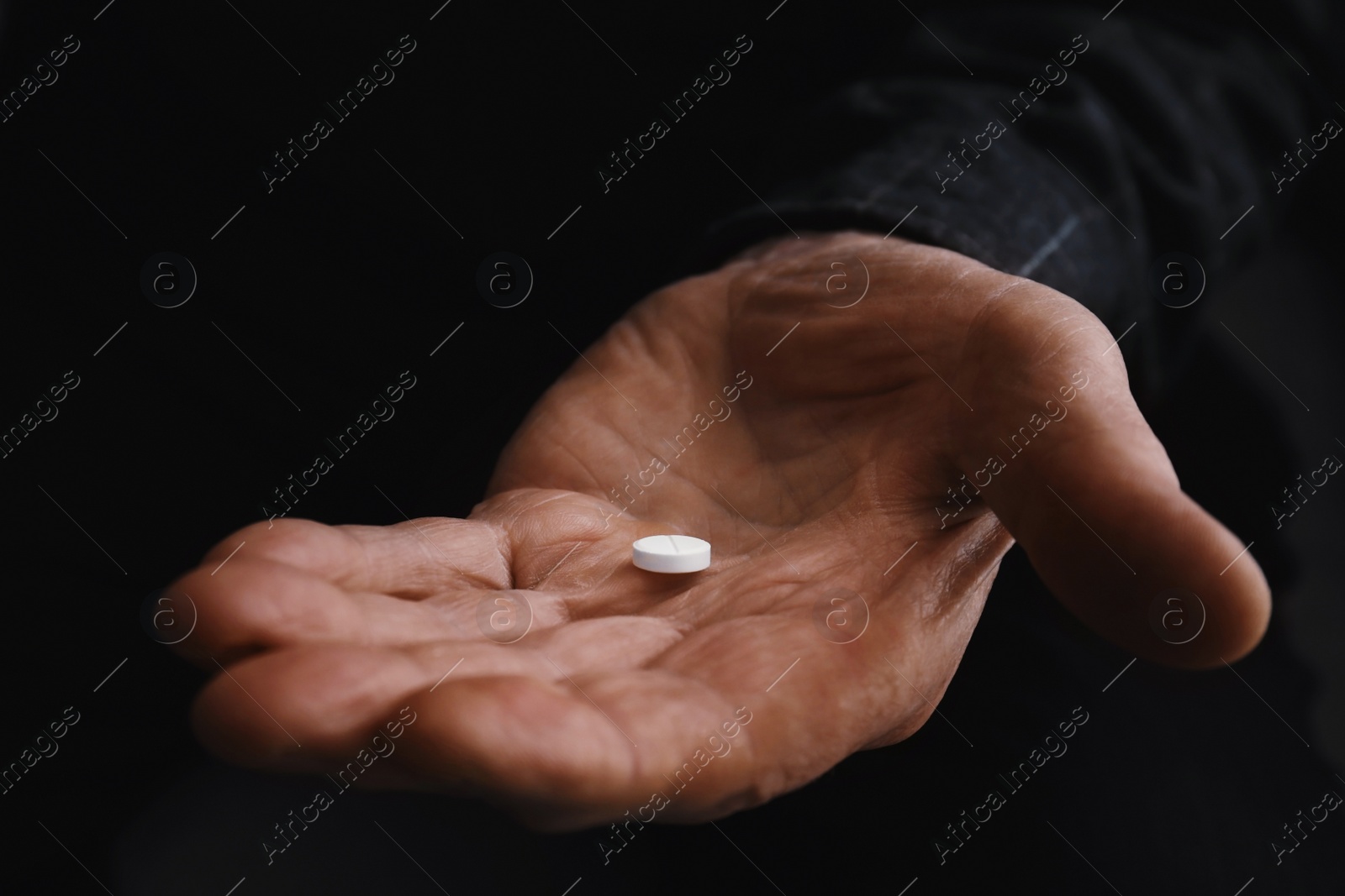 Photo of Senior man holding pill in his hand, closeup