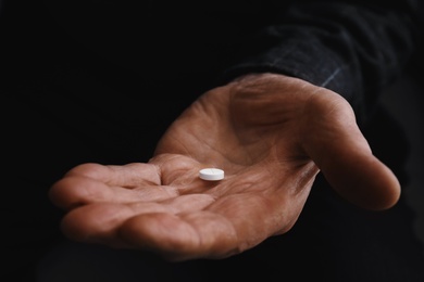 Senior man holding pill in his hand, closeup