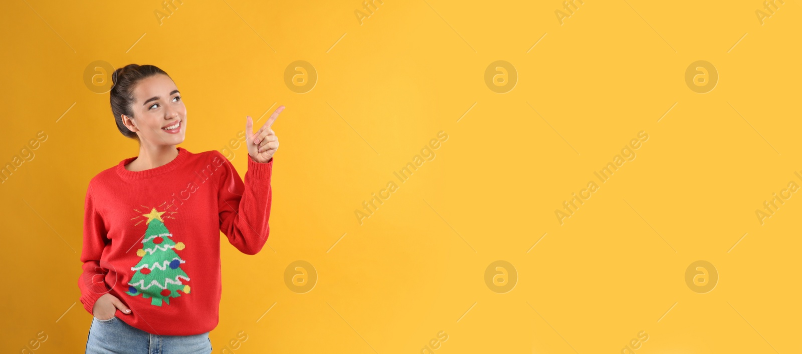 Photo of Young woman in Christmas sweater on yellow background, space for text