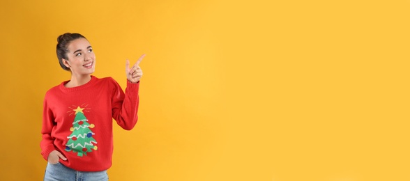 Young woman in Christmas sweater on yellow background, space for text