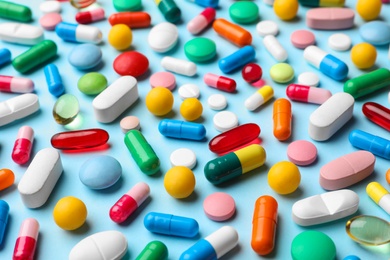 Photo of Different pills on color background, closeup view