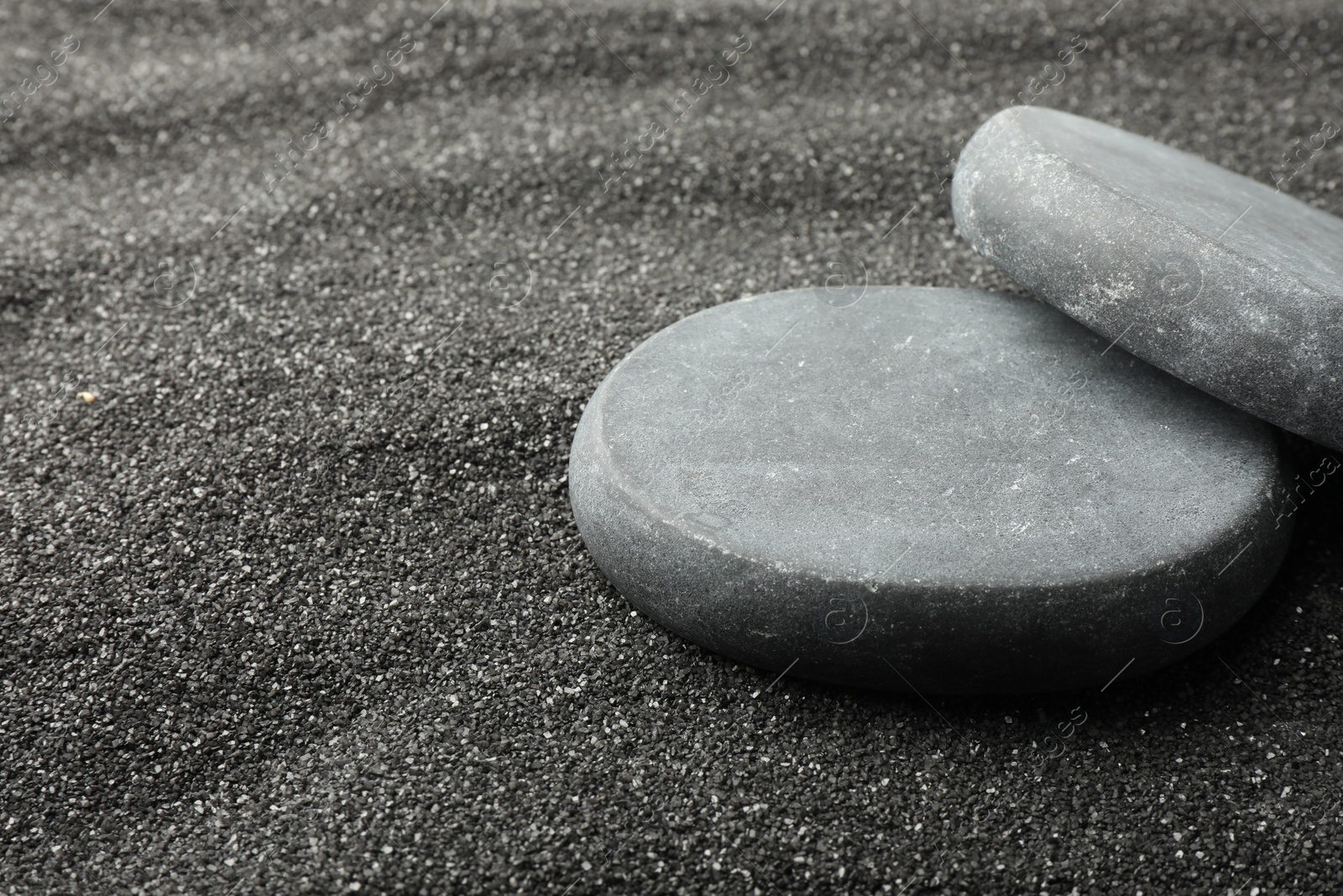 Photo of Presentation of product. Stone podiums on black sand, closeup. Space for text