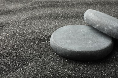 Presentation of product. Stone podiums on black sand, closeup. Space for text