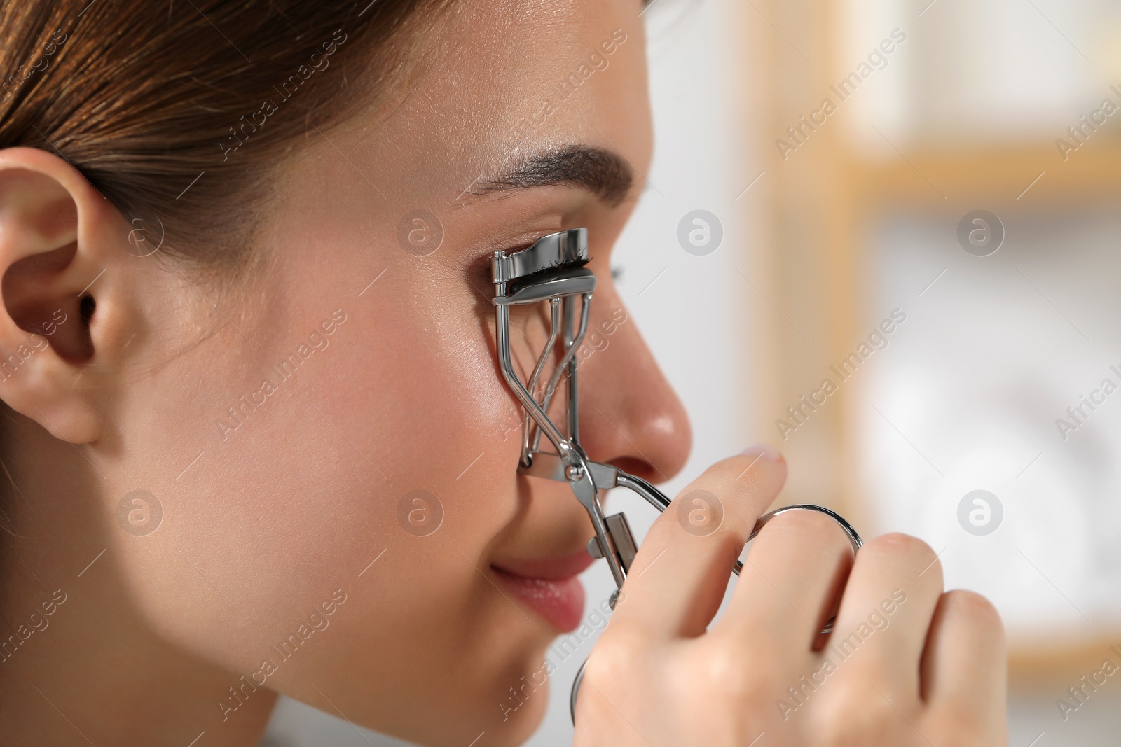 Photo of Woman using eyelash curler, closeup. Space for text