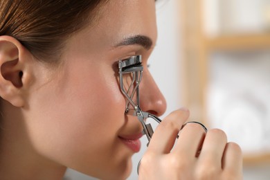 Photo of Woman using eyelash curler, closeup. Space for text