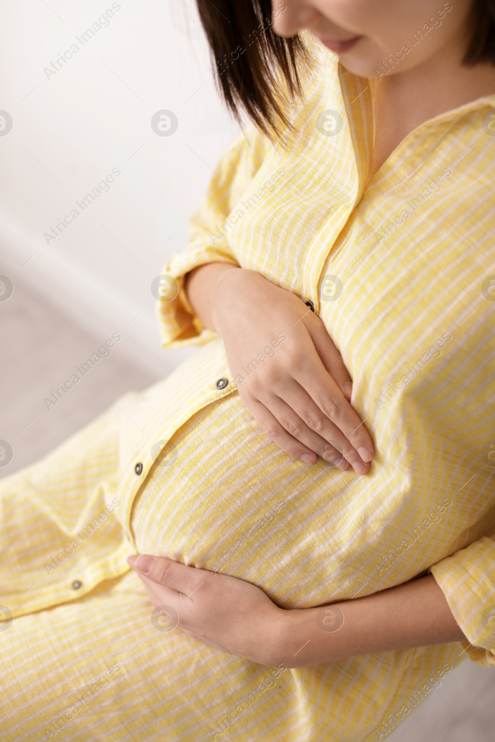 Photo of Beautiful pregnant woman sitting in light room, closeup