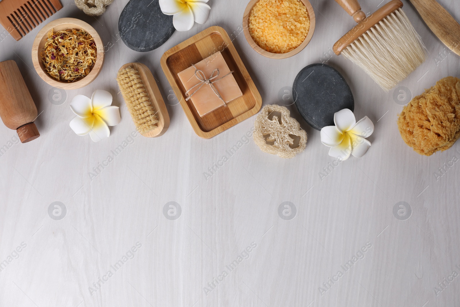 Photo of Flat lay composition with different spa products and flowers on light wooden table. Space for text