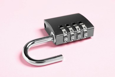 Photo of One steel combination padlock on pink background, closeup