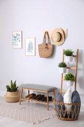 Photo of Beautiful plants and comfortable bench near white wall at home. Idea for interior design