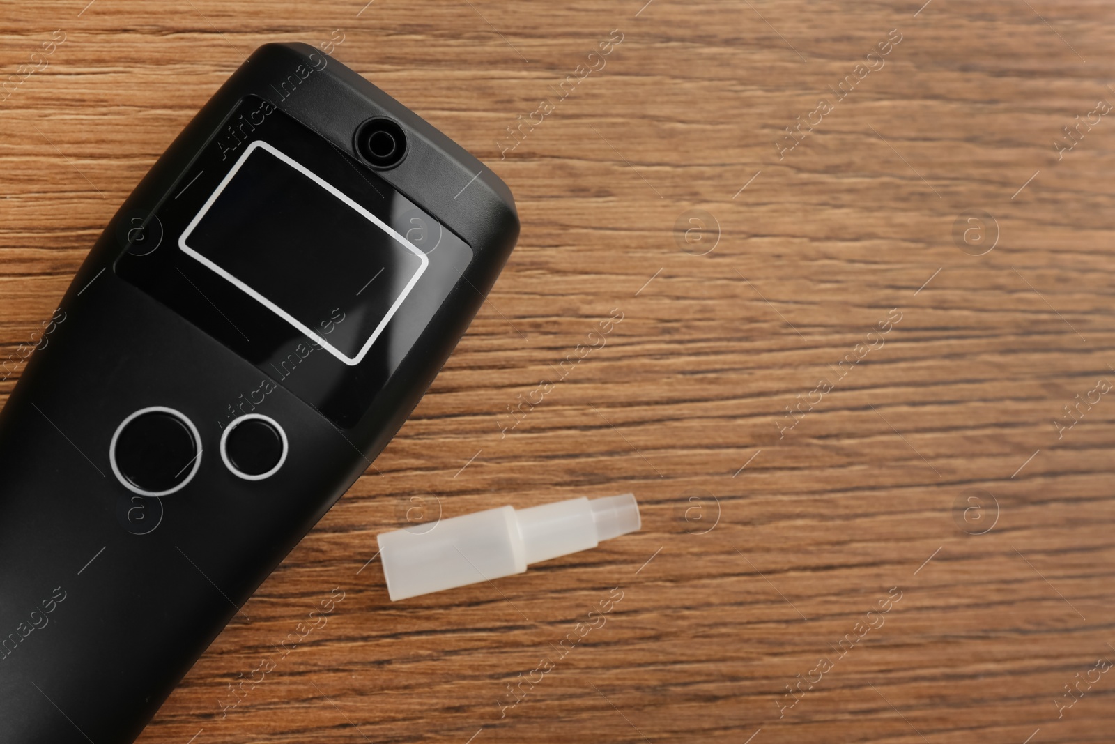 Photo of Modern breathalyzer with blank screen and mouthpiece on wooden table, flat lay. Space for text