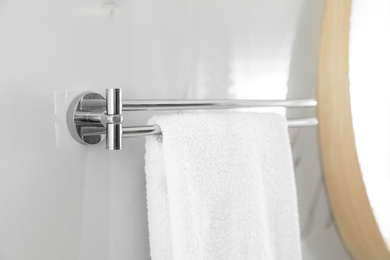 Photo of Holder with clean towel on light wall in bathroom