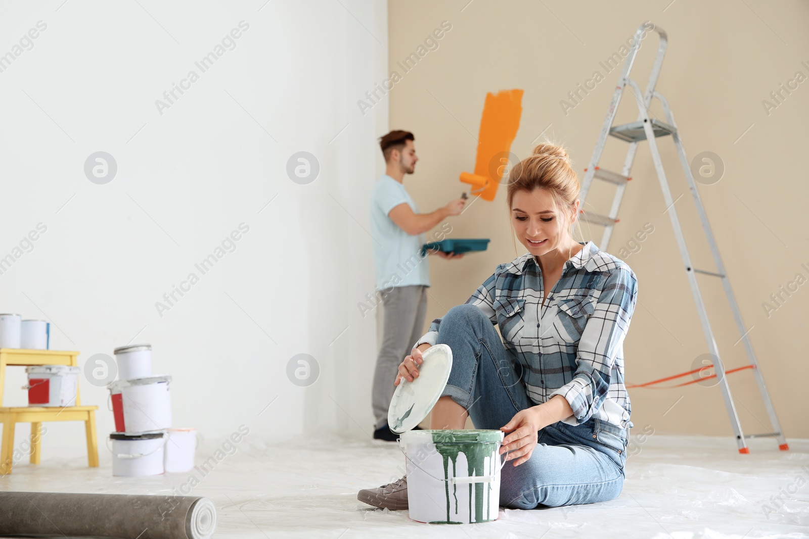 Photo of Happy couple painting wall indoors. Home repair