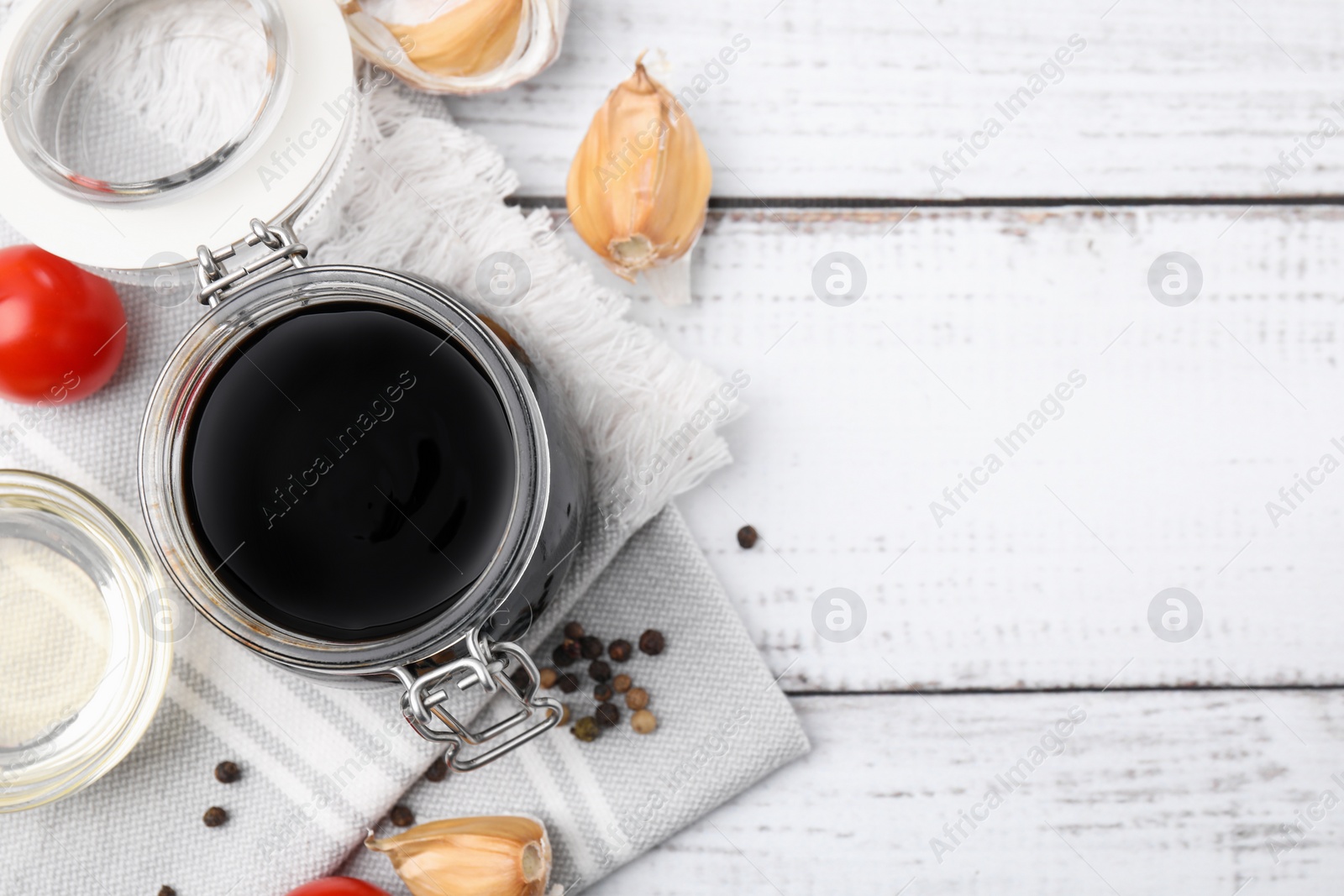 Photo of Organic balsamic vinegar and cooking ingredients on white wooden table, flat lay. Space for text