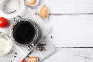 Organic balsamic vinegar and cooking ingredients on white wooden table, flat lay. Space for text