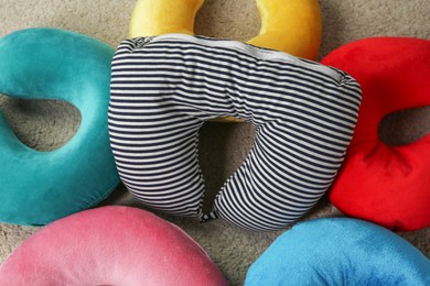 Photo of Colorful travel pillows on beige rug, top view