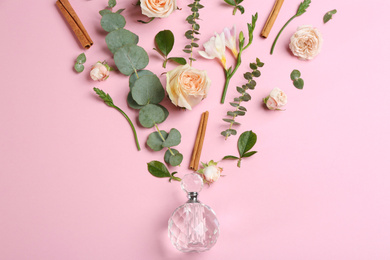 Beautiful flat lay composition with bottle of perfume, cinnamon and flowers on pink background