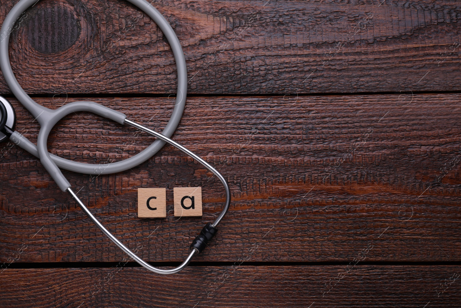 Photo of Cubes with symbol Ca (Calcium) and stethoscope on wooden table, top view. Space for text