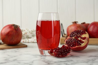 Photo of Tasty pomegranate juice in glass and fresh fruits on white marble table