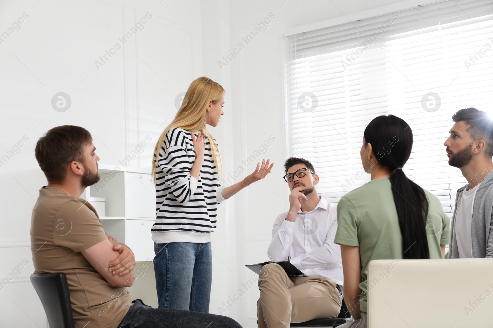 Photo of Psychotherapist working with group of drug addicted people at therapy session indoors