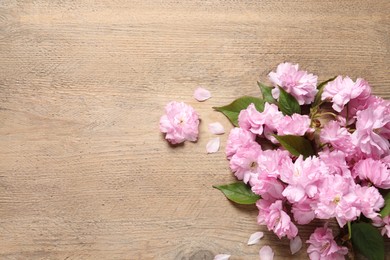 Beautiful sakura tree blossoms on wooden table, flat lay. Space for text