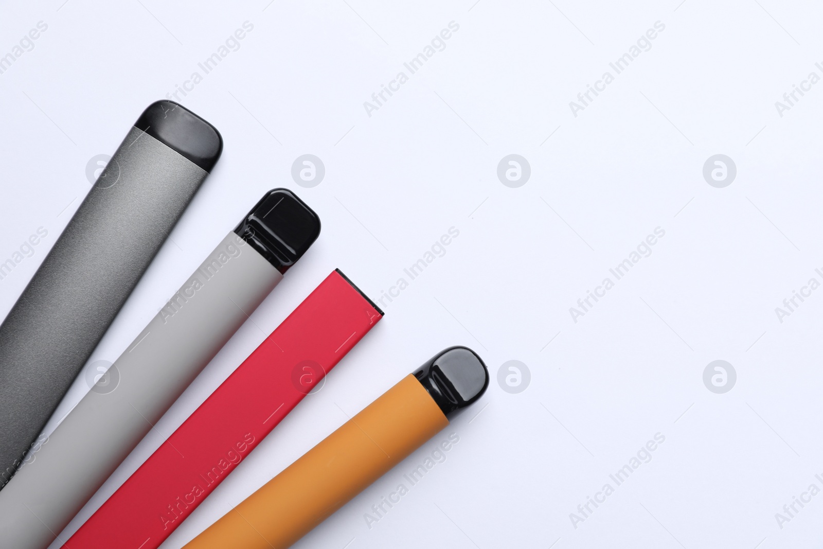 Photo of Different electronic cigarettes on white background, top view